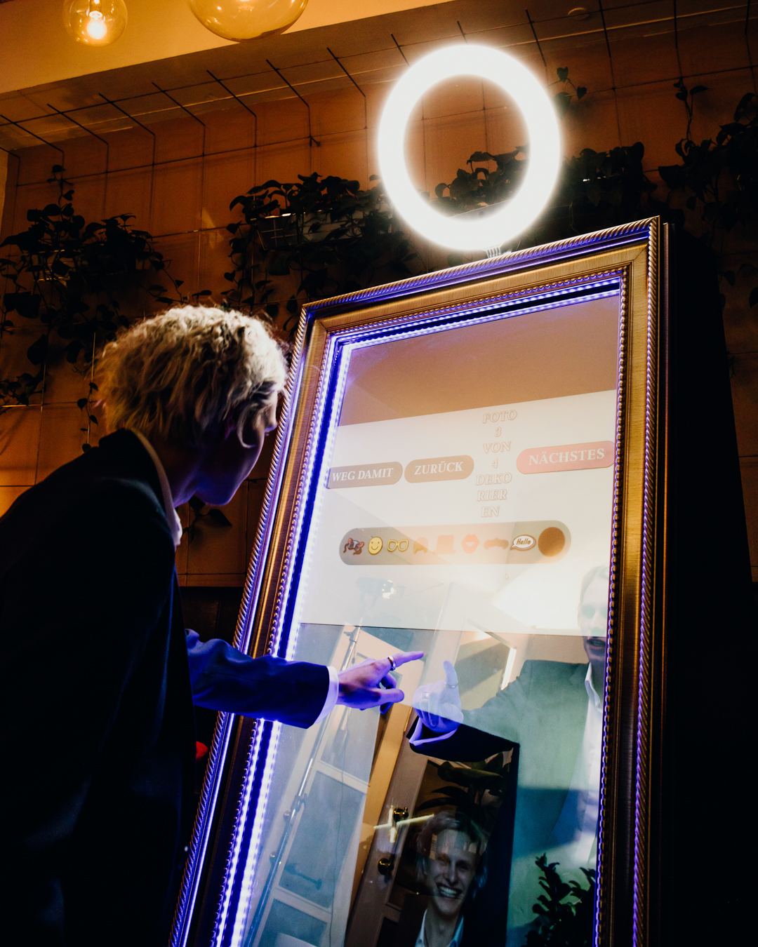 Eine Person nutzt den interaktiven Fotospiegel (Fotobox) von Glüx, umgeben von stimmungsvoller Beleuchtung und stilvoller Dekoration in einer Event-Lokalität in Bayreuth.
